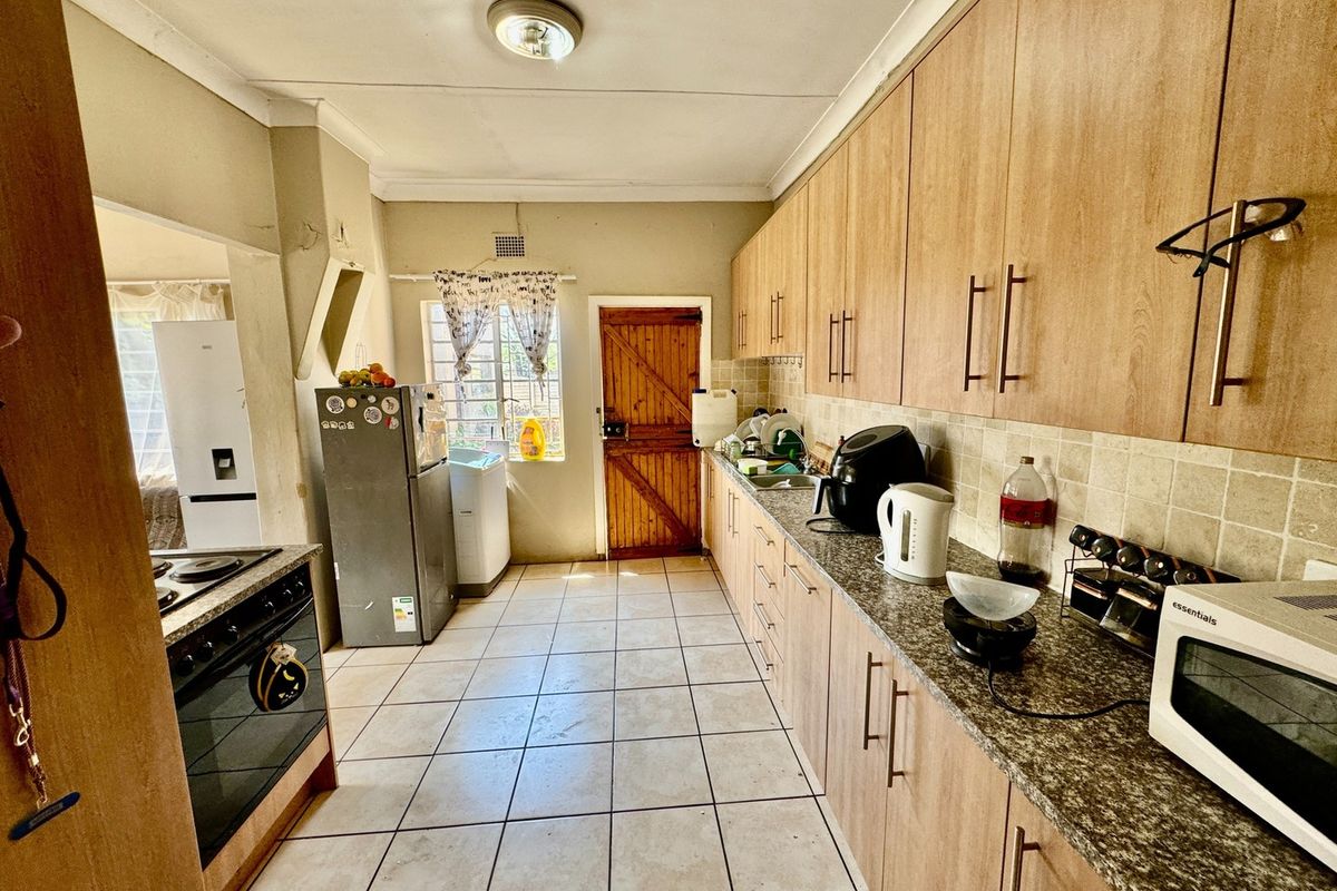 A functional kitchen featuring wood-look cabinetry, granite-style countertops, tiled flooring, and a built-in stove with extractor fan.