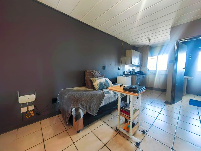 Open plan studio apartment featuring a compact kitchenette with built-in cabinetry and tiled flooring throughout.