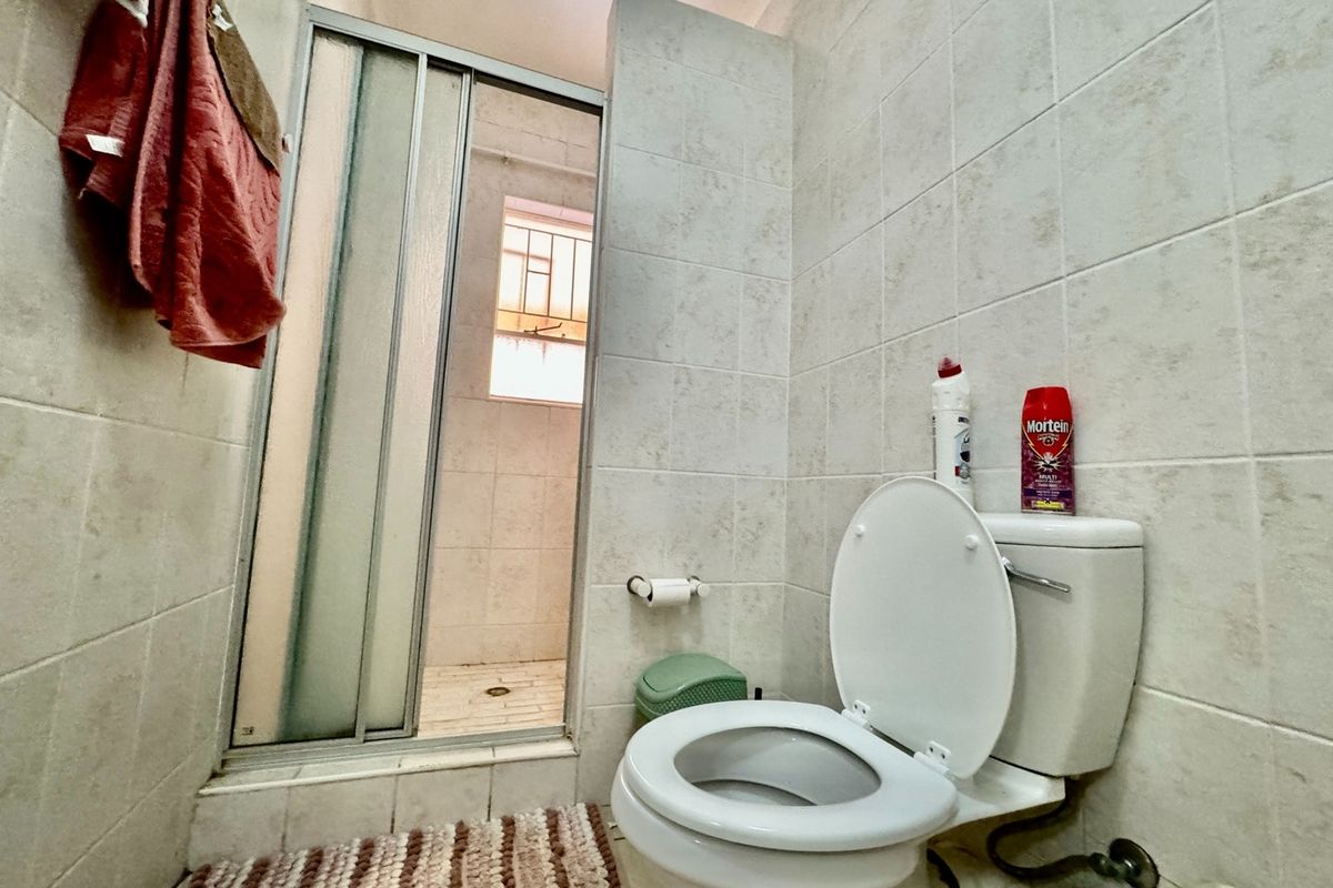 A functional bathroom featuring a tiled shower enclosure with sliding glass doors and a standard toilet.