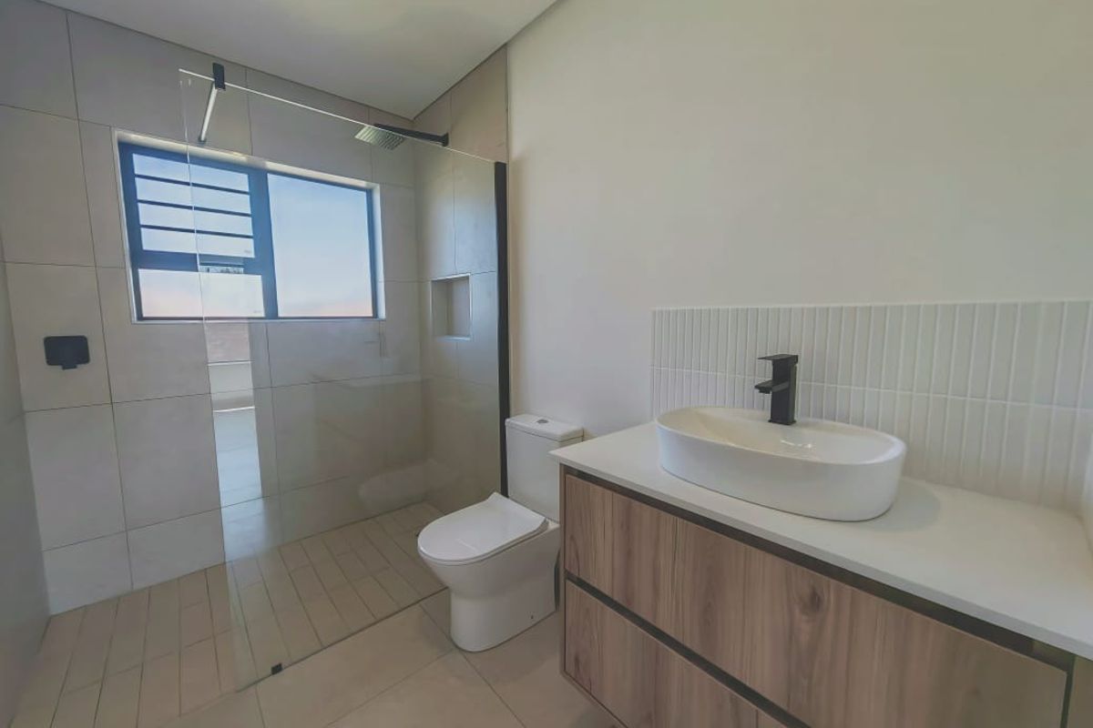 Modern bathroom featuring a floating wood-finish vanity with a vessel sink, a walk-in shower with a glass screen, and contemporary tiling.