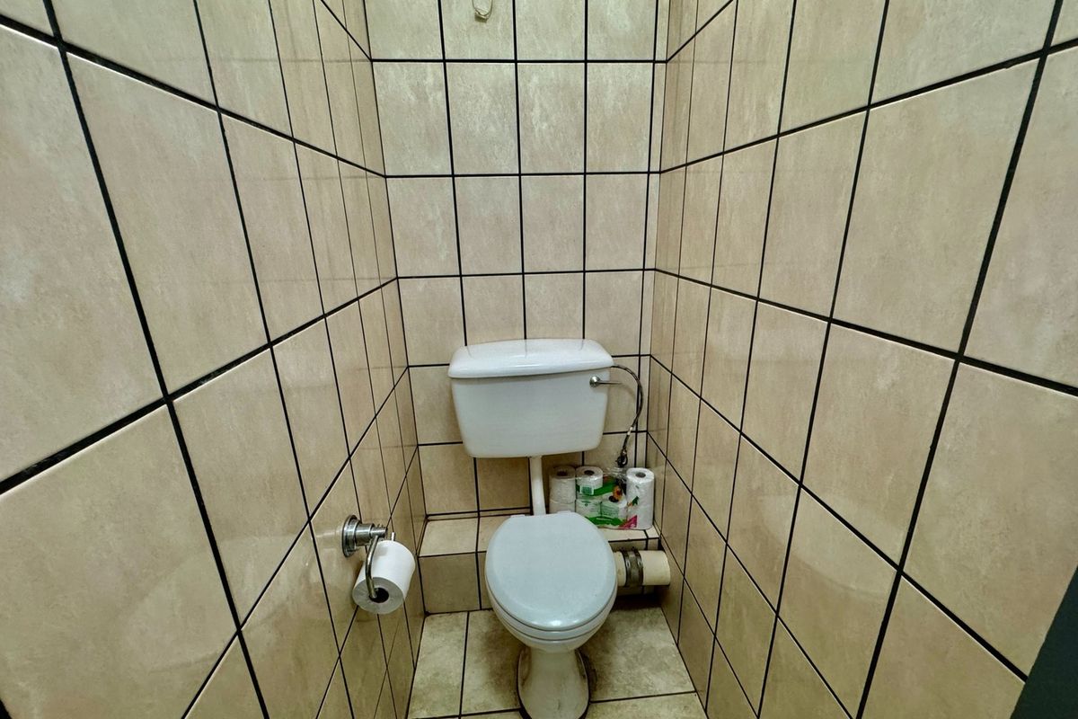 A compact bathroom featuring floor-to-ceiling tiled walls and a standard white toilet suite.
