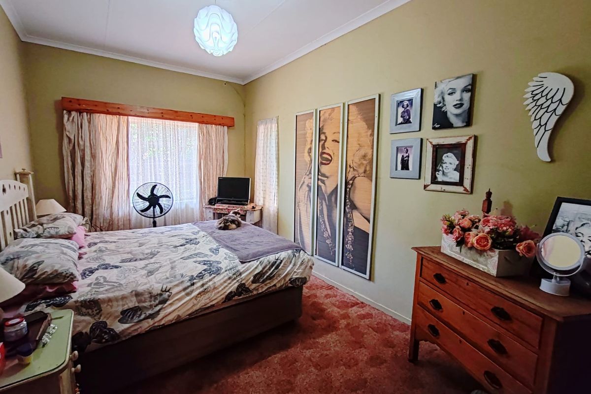 A standard bedroom featuring a ceiling rose, cornice detailing, and window treatments.