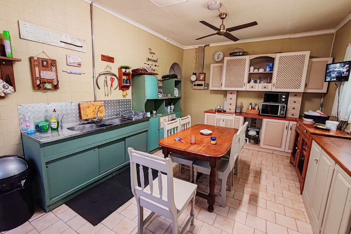 A functional kitchen featuring built-in cabinetry, a double basin sink, and tiled flooring, offering a practical layout with potential for modern updates.