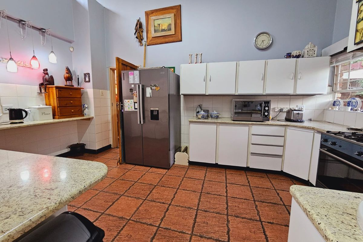 A functional kitchen featuring white cabinetry, granite-style countertops, a built-in oven, and tiled flooring with high ceilings.