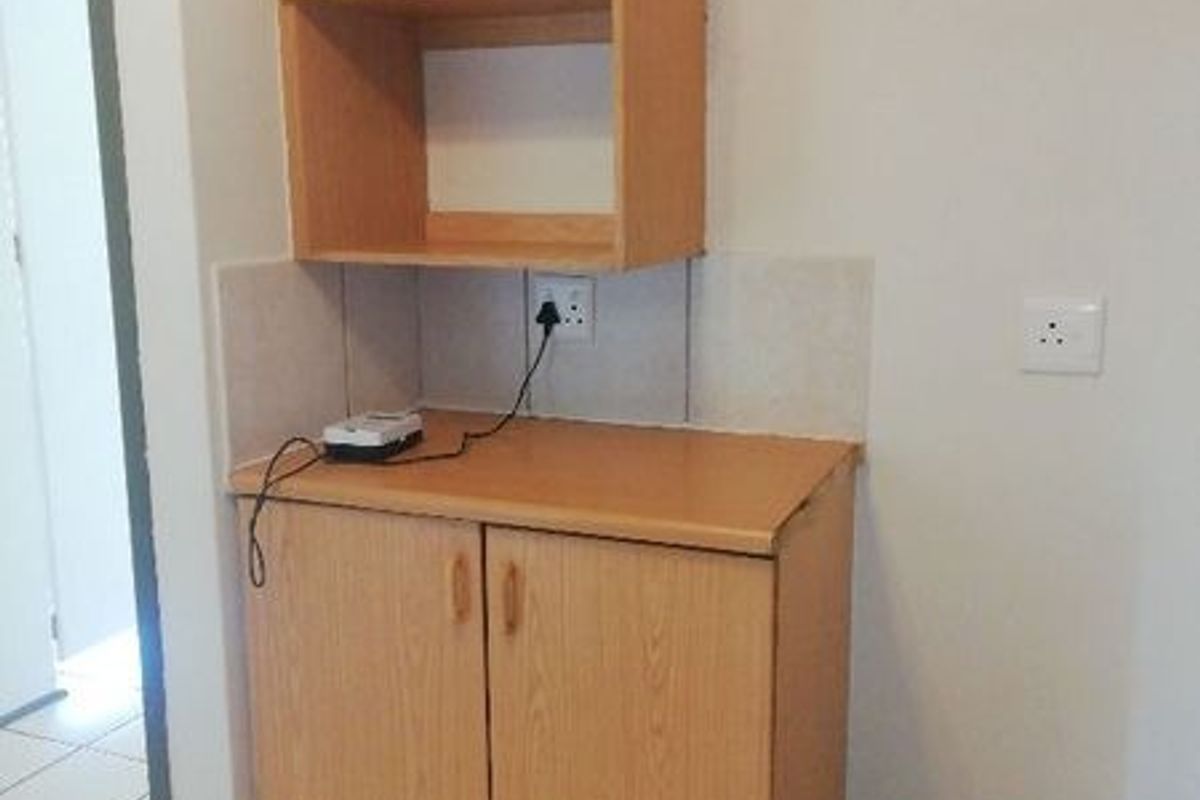 A compact kitchen utility unit featuring laminate cabinetry, tiled splashback, and integrated electrical power points.
