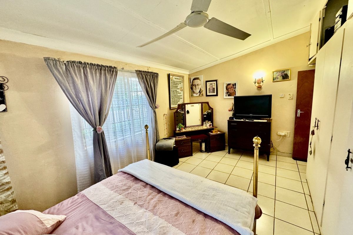 A bedroom featuring tiled flooring, a ceiling fan, and built-in wardrobe storage.