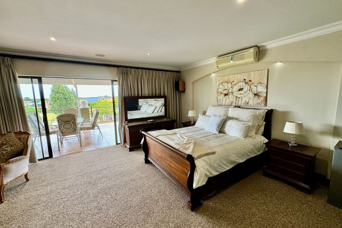 Spacious bedroom featuring neutral carpeting, recessed lighting, and large sliding glass doors opening onto a private balcony with scenic views.
