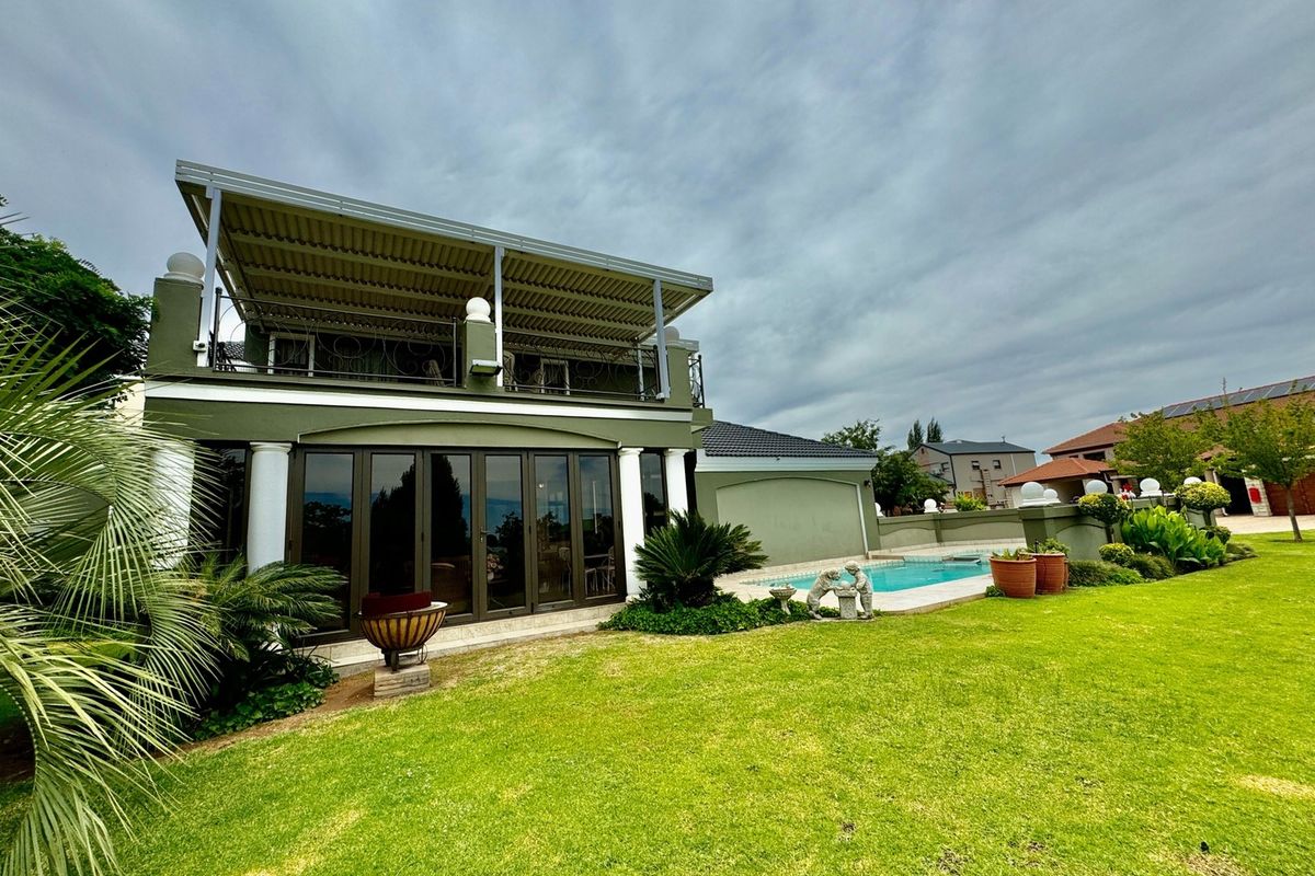 Rear view of the property featuring a covered patio, swimming pool, and a well-maintained garden area.