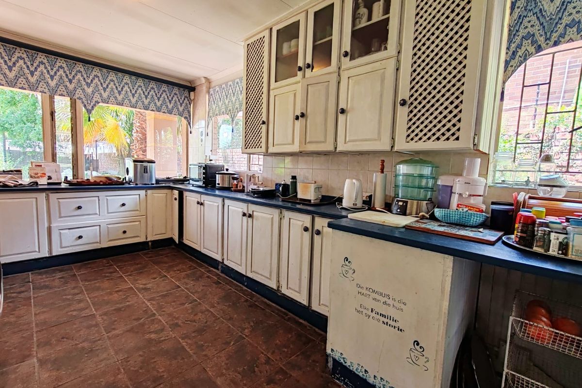 A functional kitchen featuring traditional white cabinetry, dark countertops, and tiled flooring, offering a classic layout with ample storage space.