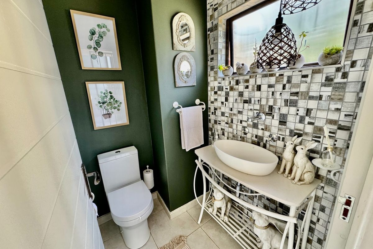 A compact powder room featuring a modern vessel sink, mosaic tile backsplash, and a wall-mounted toilet.