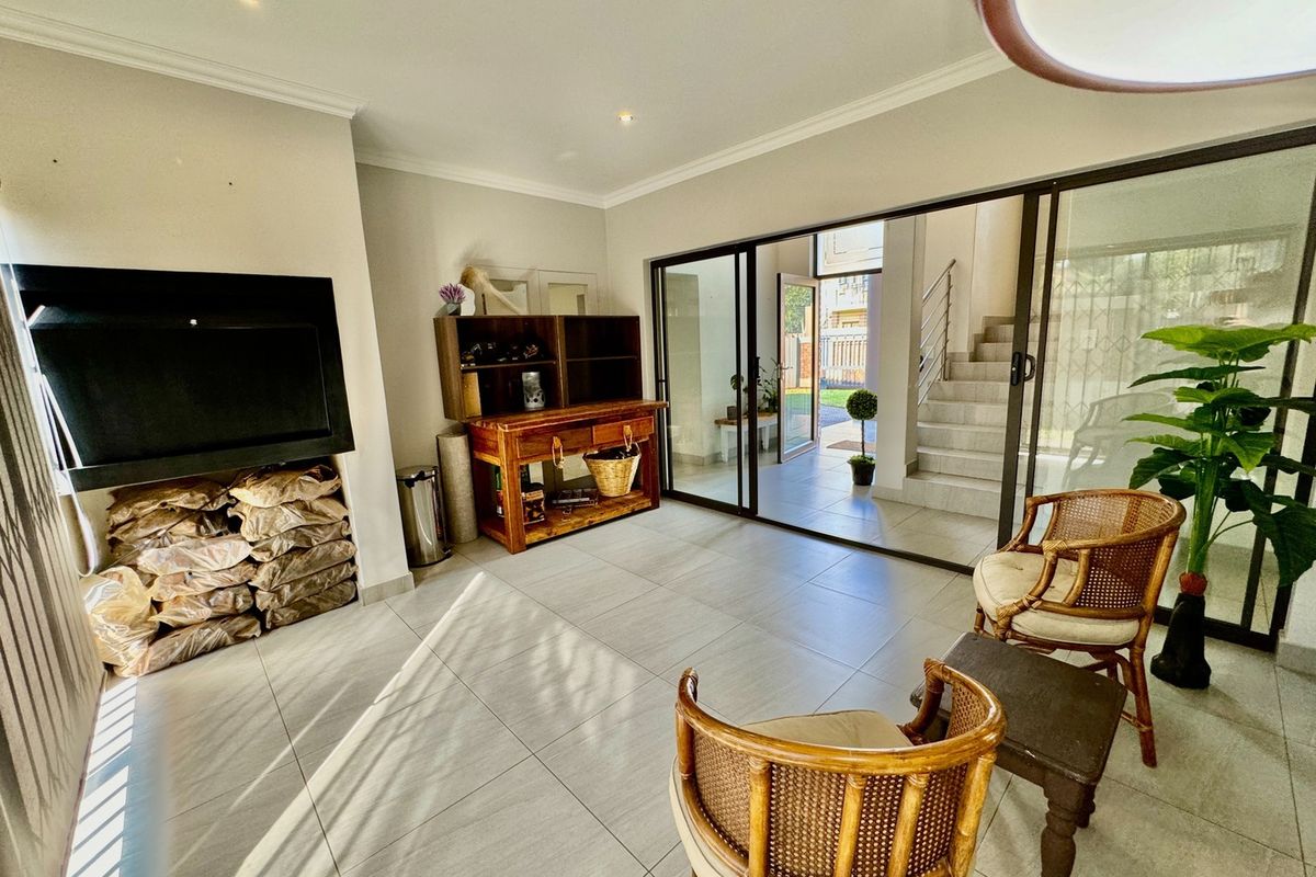 Bright living area featuring large sliding glass doors, tiled flooring, and a built-in fireplace, offering seamless access to the outdoor patio.