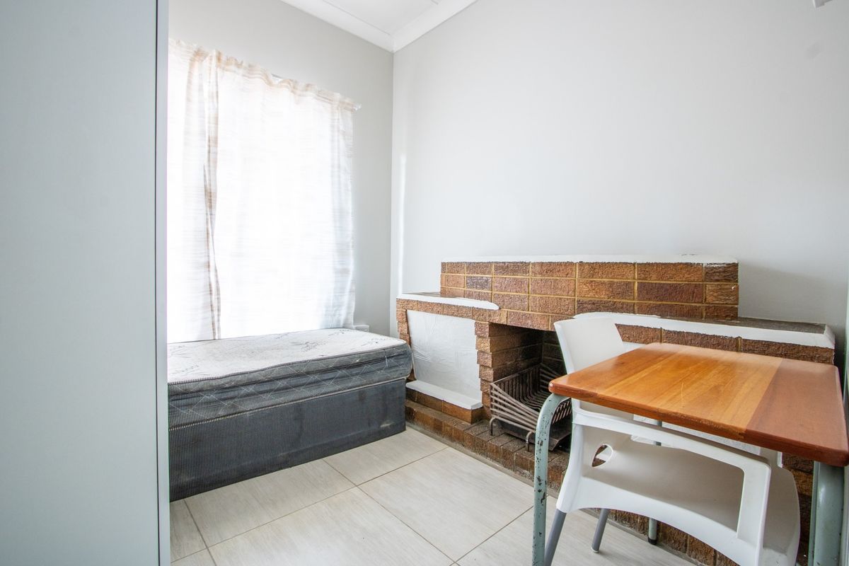A living area featuring a traditional brick fireplace and tiled flooring, offering a functional space with potential for modernization.