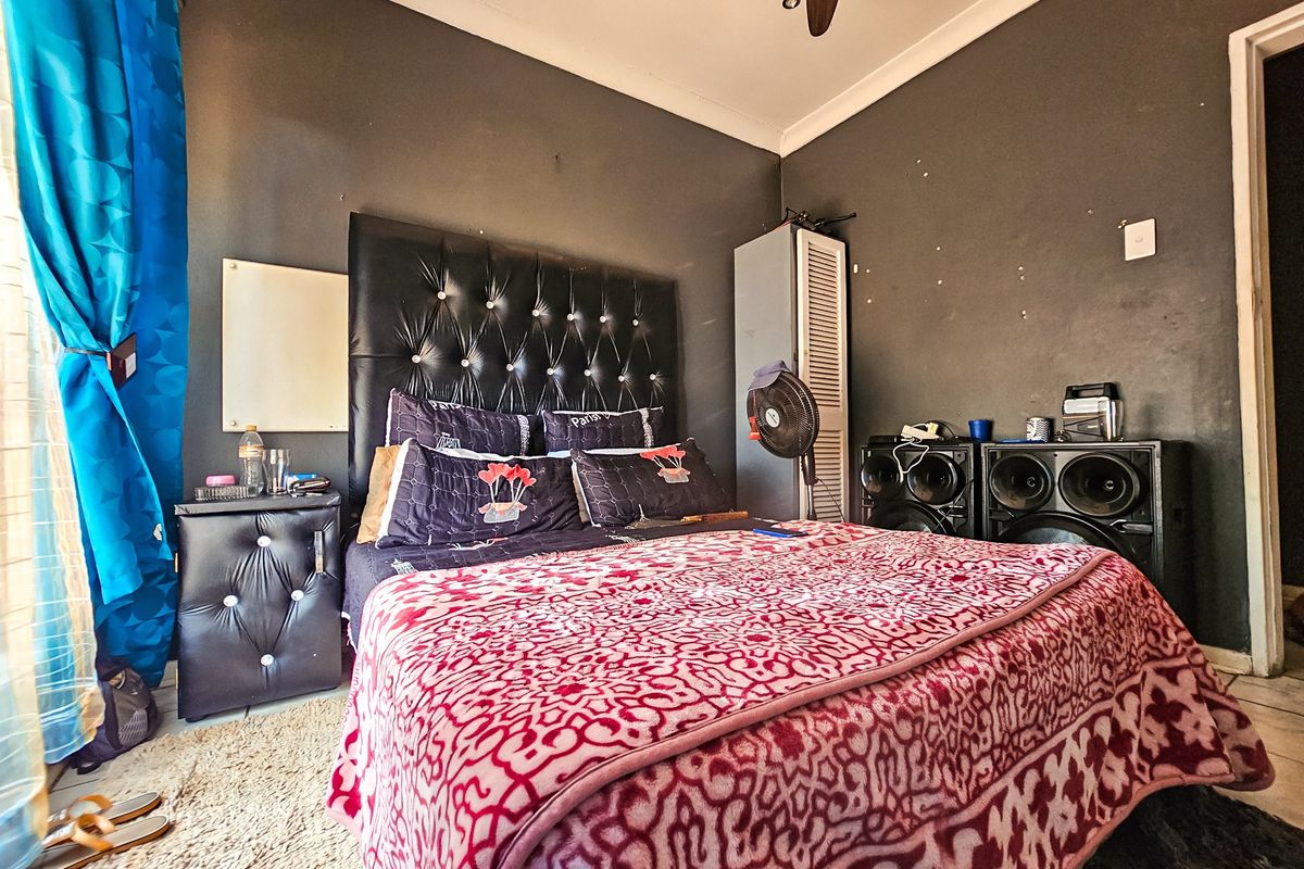 A bedroom featuring dark-toned walls, a built-in cupboard, and a ceiling fan.