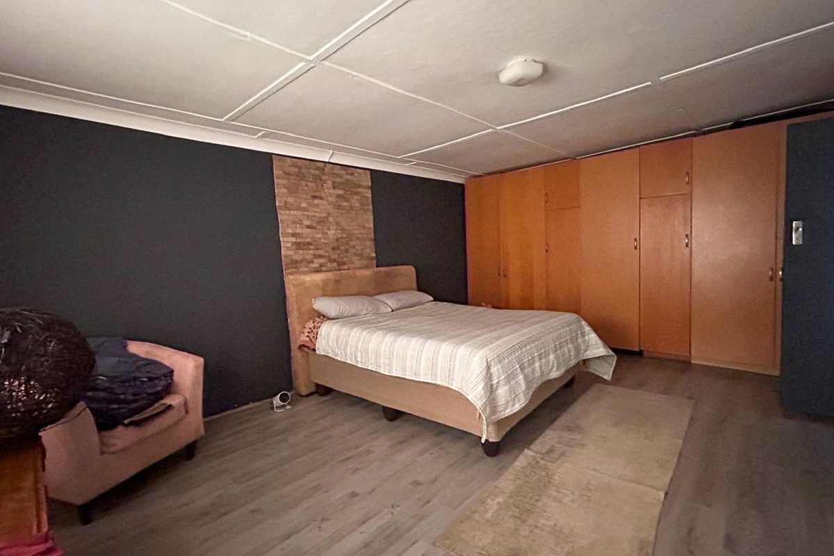 Spacious bedroom featuring built-in wooden cabinetry, laminate flooring, and a decorative stone accent wall.
