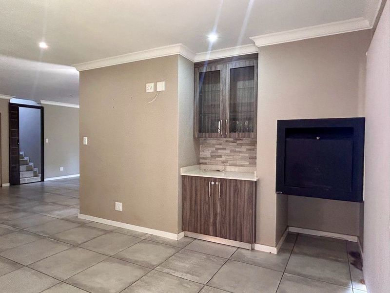 Spacious living area featuring tiled flooring, recessed lighting, built-in cabinetry with stone countertop, and a modern built-in fireplace.