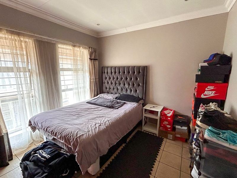 A bedroom featuring tiled flooring, neutral wall tones, and large windows that provide natural light.