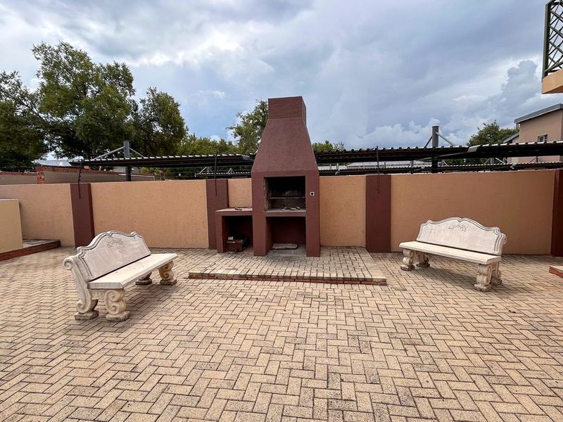 A paved outdoor patio area featuring a built-in brick braai and perimeter boundary walls with electric fencing.