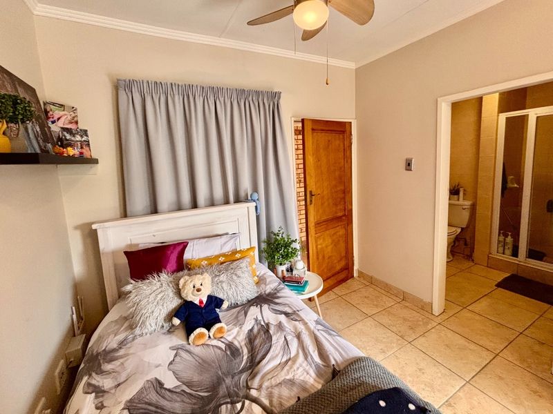 A bedroom featuring tiled flooring, a ceiling fan, and direct access to an en-suite bathroom.