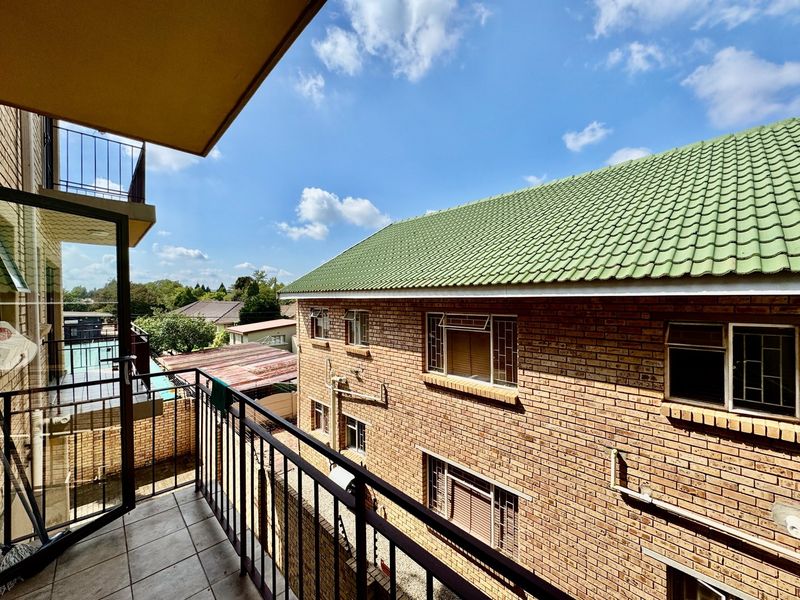 A view from a balcony overlooking the exterior brick facade and tiled roof of the apartment complex.