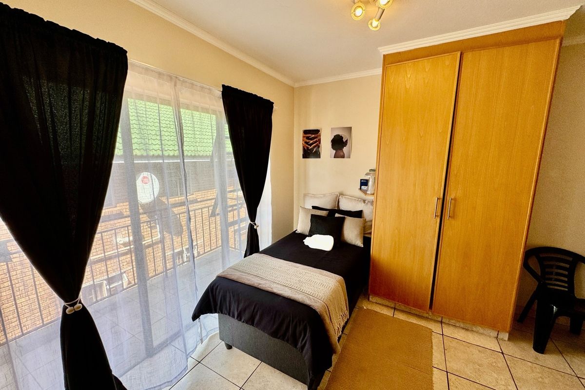 A bedroom featuring tiled flooring, a built-in wooden wardrobe, and a sliding glass door providing access to a balcony.