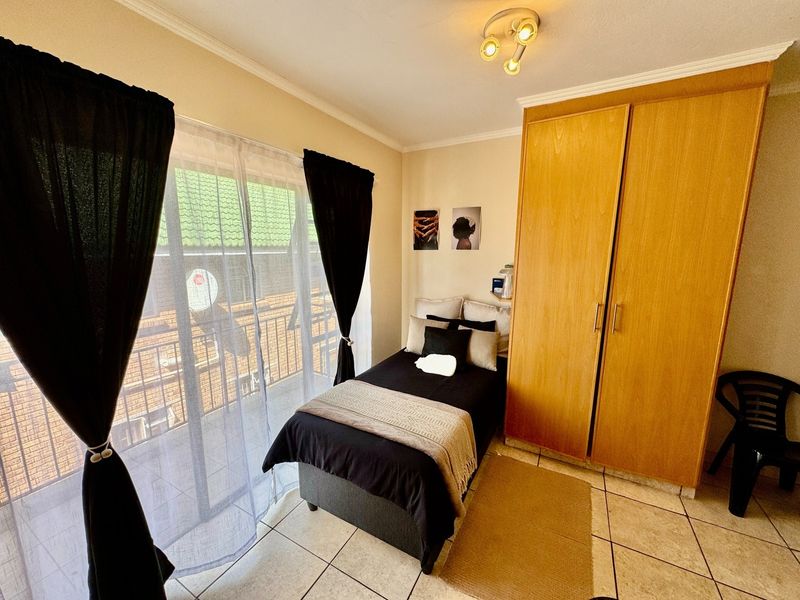 A bedroom featuring tiled flooring, a built-in wooden wardrobe, and a sliding glass door providing access to a balcony.