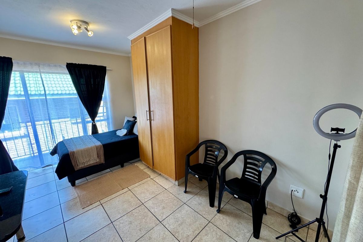 Bedroom featuring tiled flooring, a built-in wooden wardrobe, and a sliding glass door providing access to an outdoor balcony area.