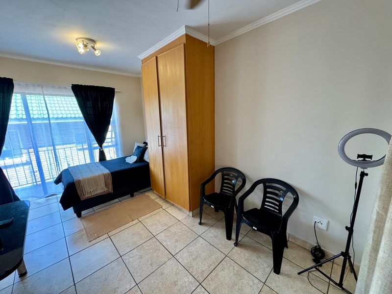 Bedroom featuring tiled flooring, a built-in wooden wardrobe, and a sliding glass door providing access to an outdoor balcony area.