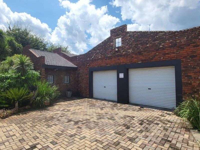 A double garage featuring a classic brick exterior, roller doors, and a well-maintained paved driveway area.
