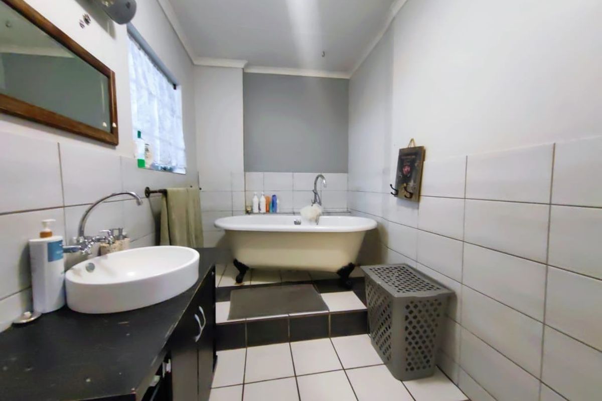A bathroom featuring a classic freestanding bathtub, a modern vessel sink set on a vanity cabinet, and tiled wall and floor finishes.