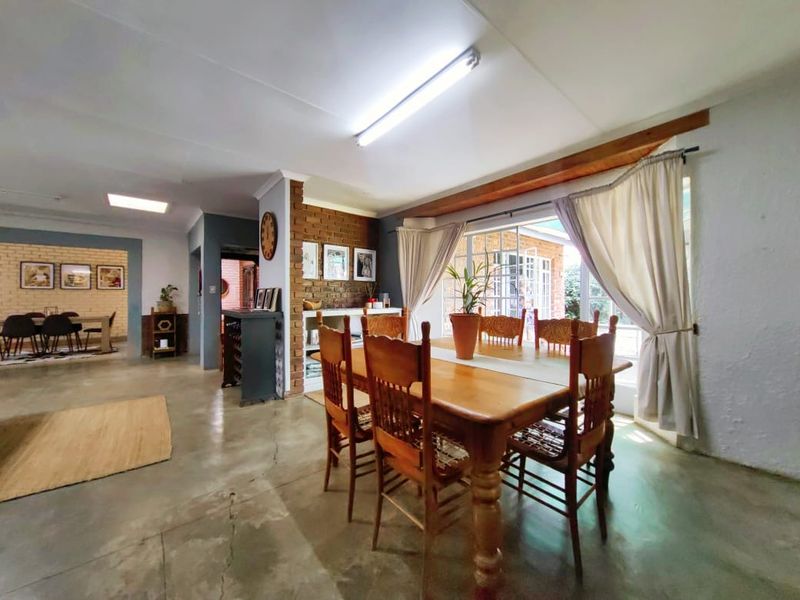 Spacious open-plan dining area featuring polished concrete floors, an exposed brick feature wall, and large windows allowing for natural light.