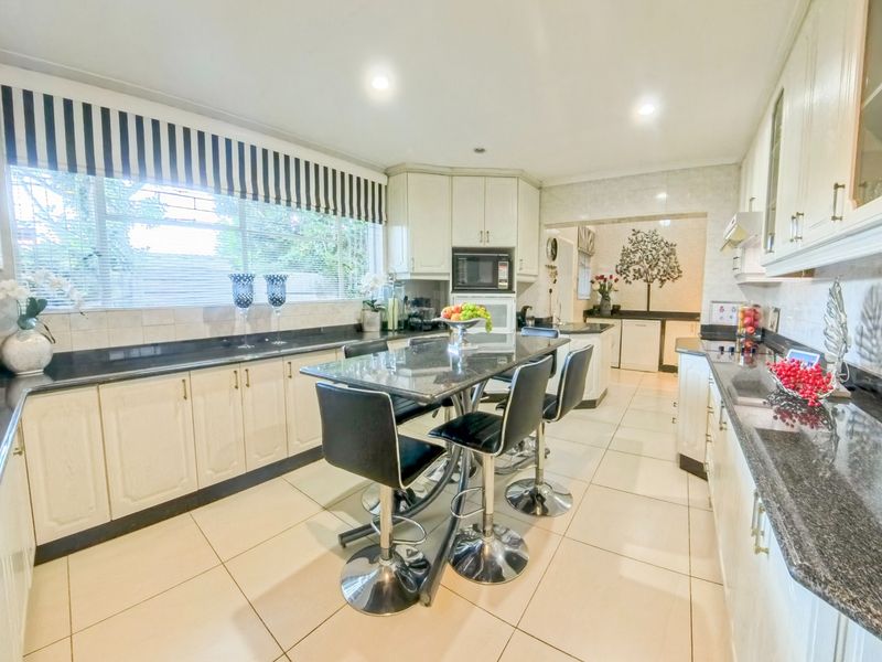 Spacious kitchen featuring granite countertops, ample built-in cabinetry, a central breakfast bar, and tiled flooring, offering a functional and well-lit culinary space.