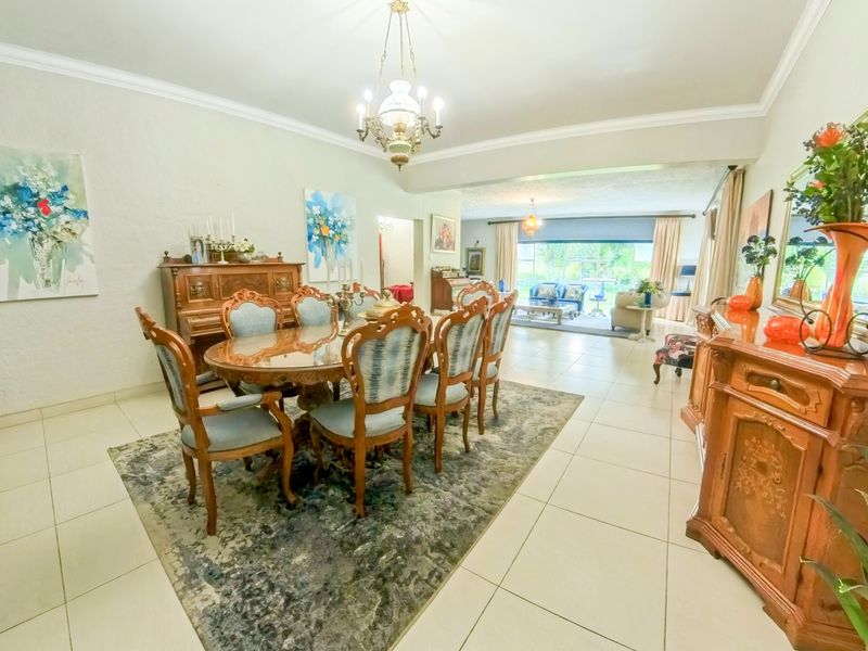 Spacious open-plan dining and living area featuring tiled flooring, coved cornicing, and large sliding glass doors leading to the outdoor space.
