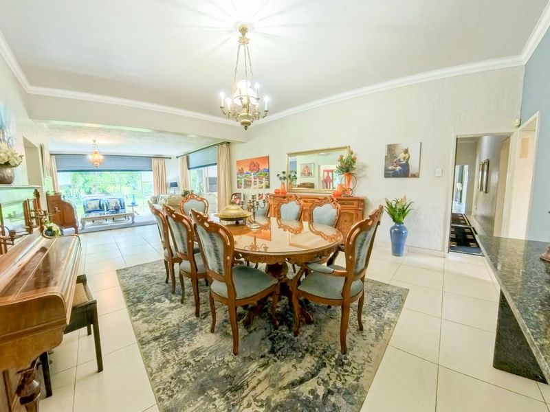 Spacious dining room featuring tiled flooring, elegant cove cornicing, a central chandelier, and a built-in granite serving counter.