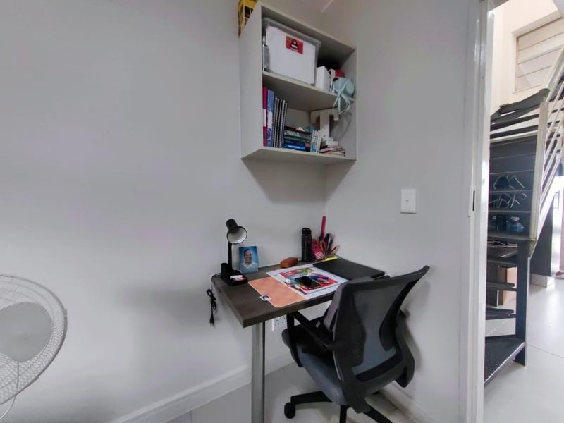 A compact home office space featuring a wall-mounted storage shelf and neutral finishes, providing a functional area for work or study.