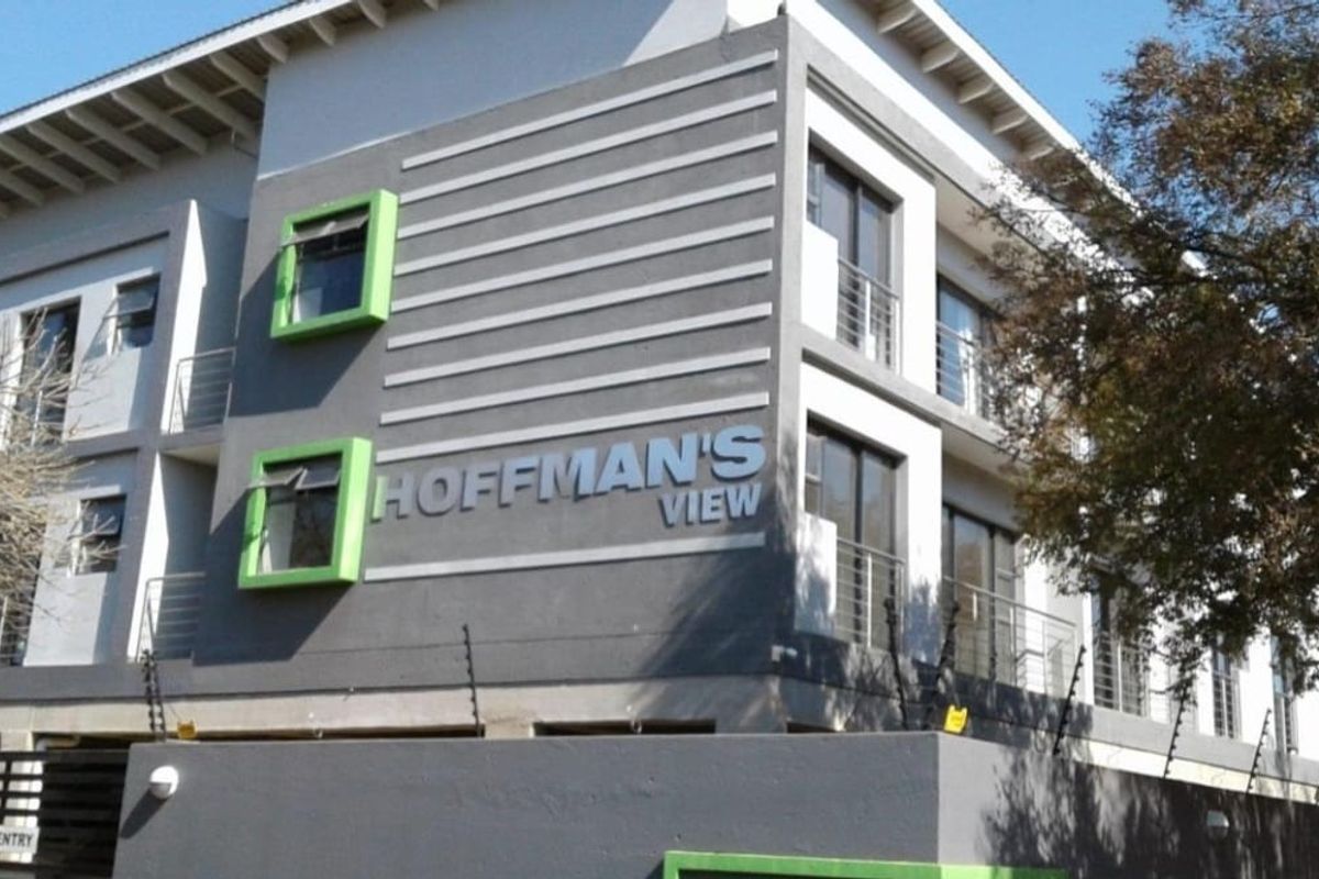 Exterior view of the Hoffman's View apartment complex, featuring modern grey facade, green accents, and balcony access.