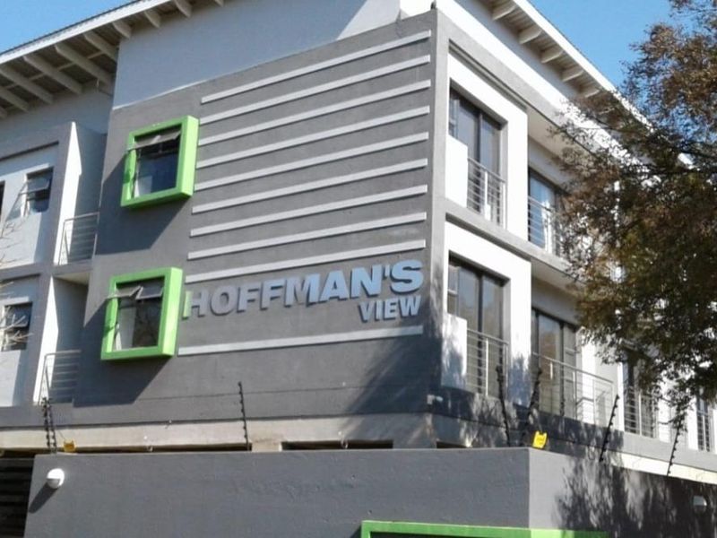 Exterior view of the Hoffman's View apartment complex, featuring modern grey facade, green accents, and balcony access.