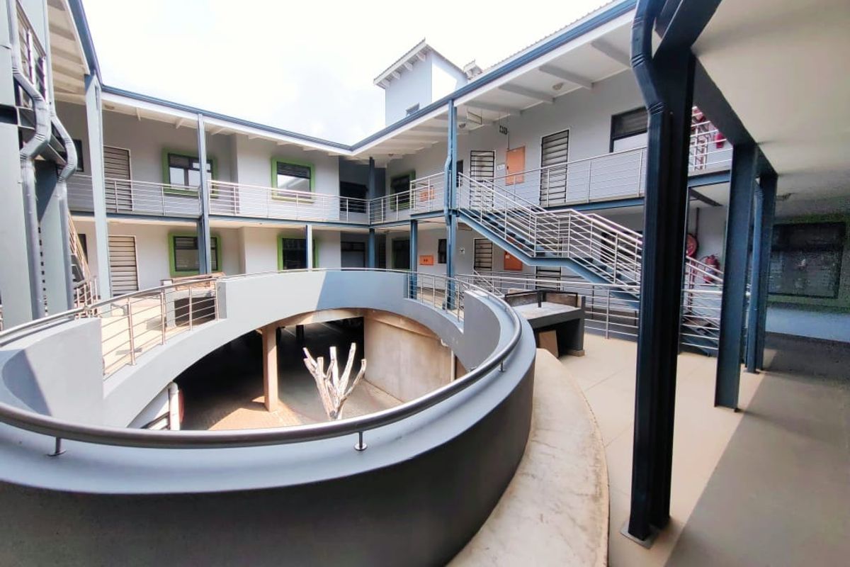 A modern apartment complex courtyard featuring a central circular void, steel staircases, and elevated walkways with stainless steel balustrades.