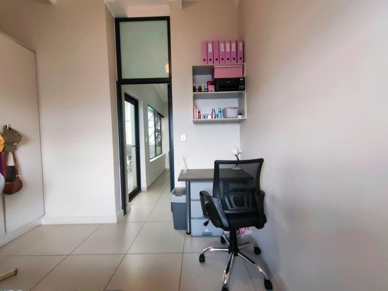 A functional home office space featuring tiled flooring, a built-in cupboard, and a transom window, providing a clean and practical work environment.