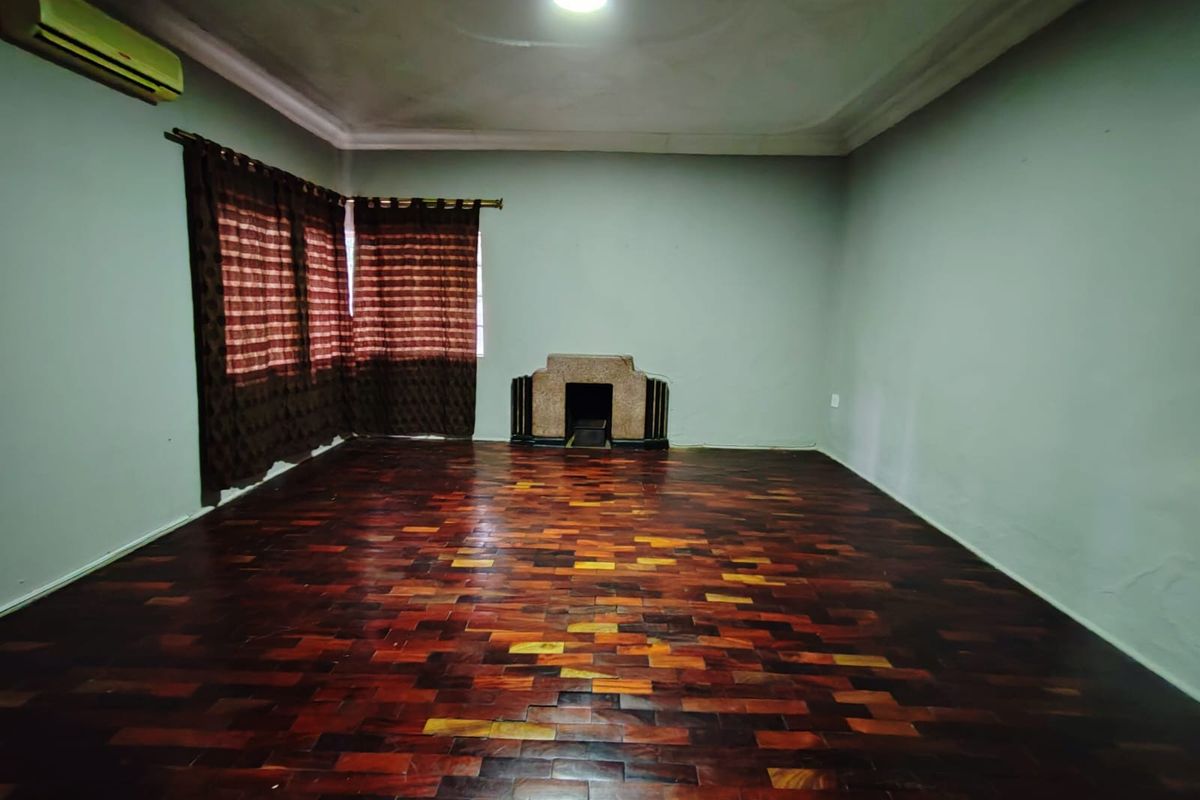 Spacious living room featuring dark parquet flooring, a central fireplace, and an installed air conditioning unit, offering a blank canvas for interior design.