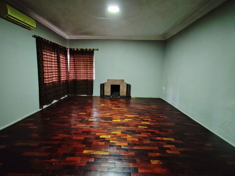 Spacious living room featuring dark parquet flooring, a central fireplace, and an installed air conditioning unit, offering a blank canvas for interior design.