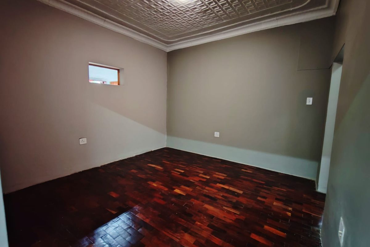 An empty bedroom featuring polished parquet flooring and a decorative pressed metal ceiling with coving.