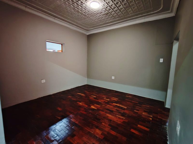 An empty bedroom featuring polished parquet flooring and a decorative pressed metal ceiling with coving.