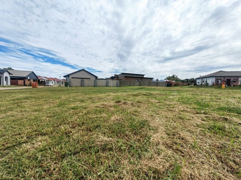 A vacant residential plot featuring a level grass lawn and established boundary walls, situated within a developed residential estate.