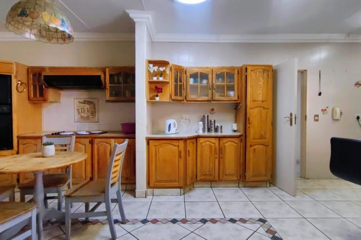 A functional kitchen featuring traditional wooden cabinetry, built-in oven, extractor fan, and tiled flooring with a decorative border.