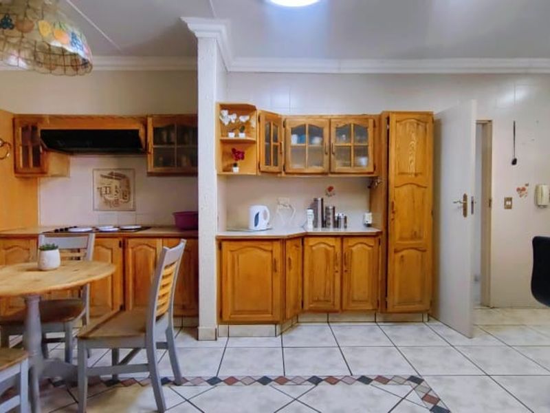 A functional kitchen featuring traditional wooden cabinetry, built-in oven, extractor fan, and tiled flooring with a decorative border.