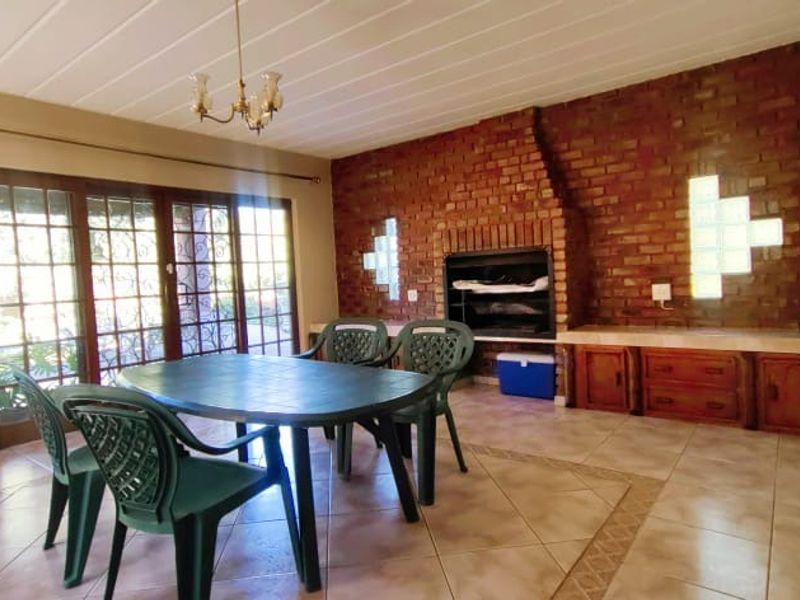 Spacious living area featuring a prominent brick fireplace, built-in cabinetry, tiled flooring, and direct access to the exterior via sliding glass doors.