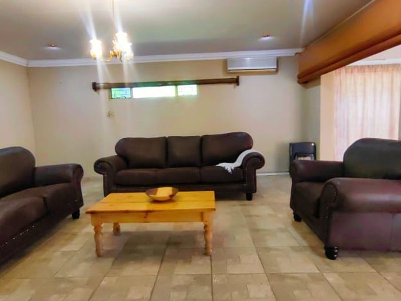 Spacious living room featuring tiled flooring, recessed lighting, and an integrated air conditioning unit, providing a comfortable and functional living space.