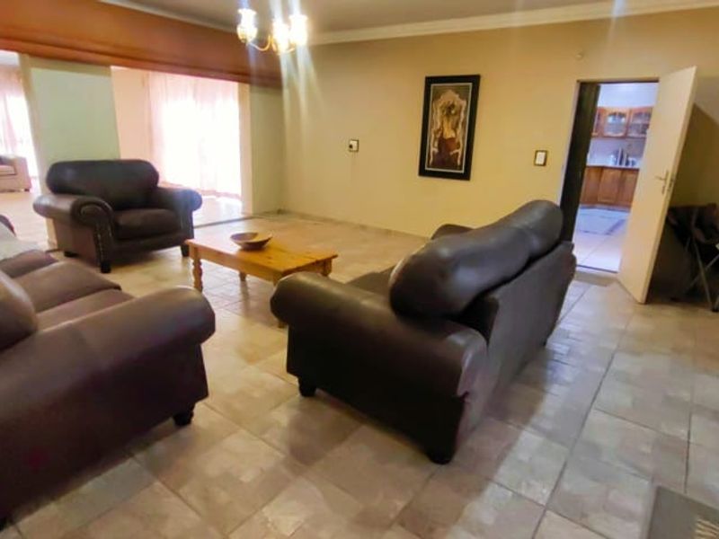 Spacious living room featuring tiled flooring, cove lighting, and sliding glass doors leading to an outdoor area.