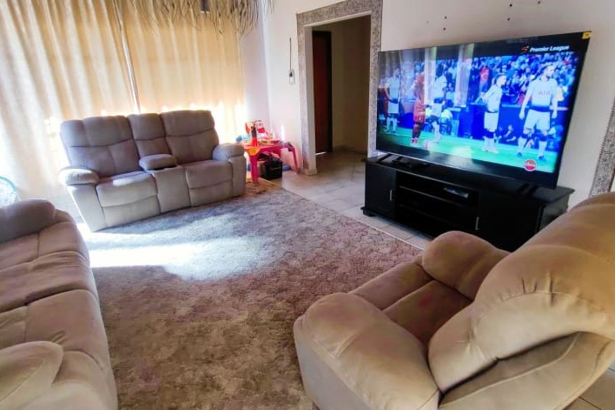 A living room featuring tiled flooring and a timber door frame, currently used as a casual lounge area.
