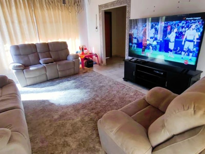 A living room featuring tiled flooring and a timber door frame, currently used as a casual lounge area.